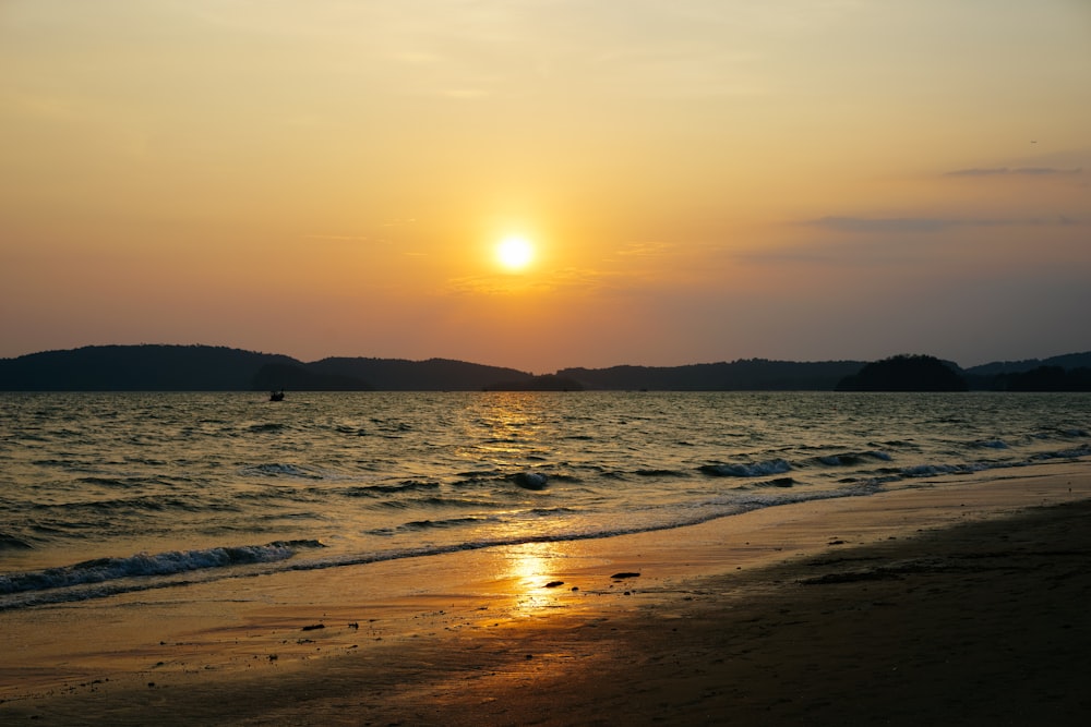 the sun is setting over the water at the beach