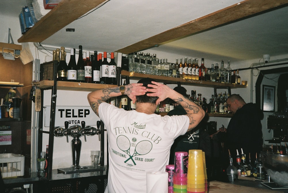 a man standing in front of a bar with lots of bottles