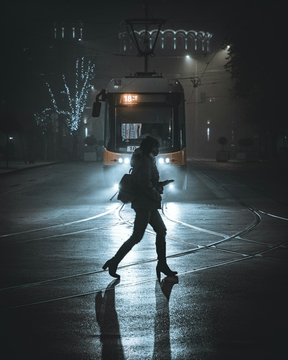 a woman walking across a street at night