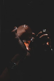 Hands holding a glowing talisman over a desk with work documents and a cup of coffee.