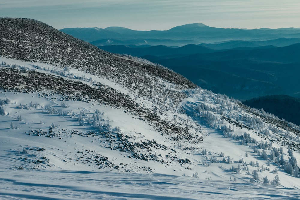 a snow covered mountain with trees and mountains in the background