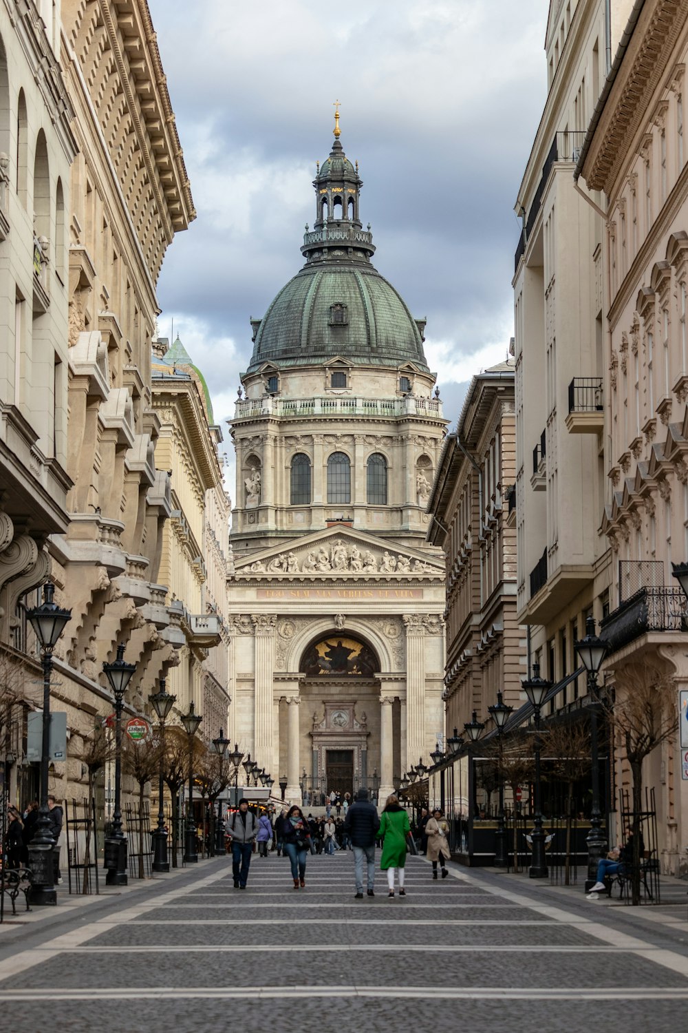 a group of people walking down a street next to tall buildings