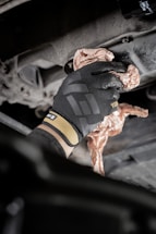 a person in black gloves working on a car