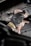 A gloved hand is wiping or cleaning a mechanical part, possibly an engine or a machine, using a crumpled cloth or paper. The setting appears industrial or mechanical, with a focus on maintenance.