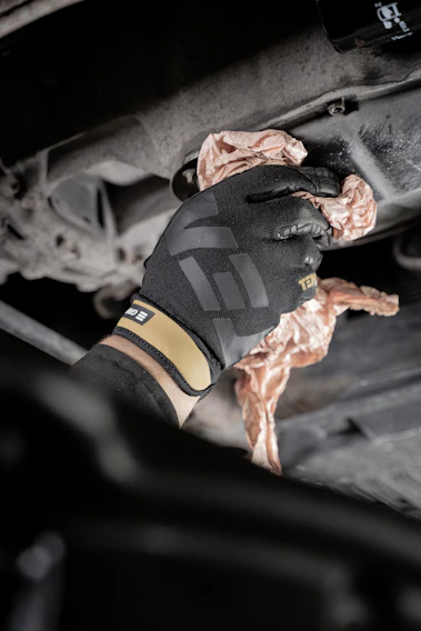 Close-up of a technician carefully scraping thick grease buildup from an industrial exhaust vent.