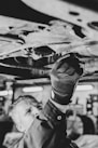 a black and white photo of a man working on a vehicle