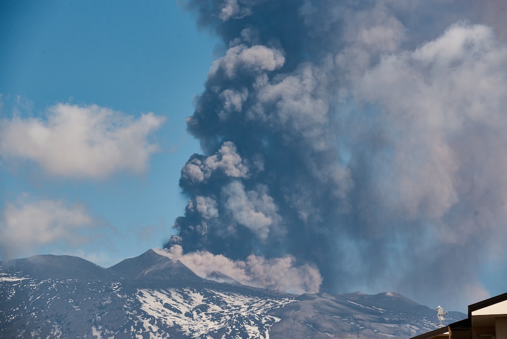 a large plume of smoke billows from a mountain