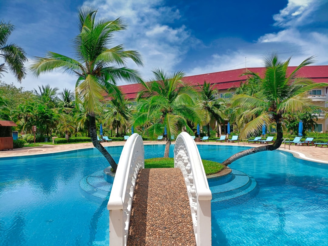a swimming pool with palm trees in the background, Pool swimming in a luxury tropical hotel