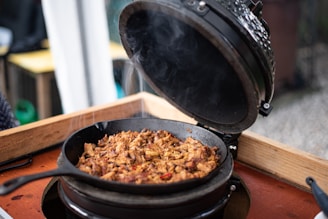 A rustic cast iron skillet sizzling with a hearty West Texas stew, set on a weathered wooden table.
