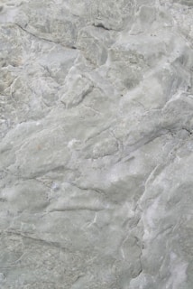A close-up view of a textured stone surface with various shades of green. The surface features intricate patterns and natural formations, giving it a rugged and earthy appearance.