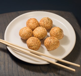 a white plate topped with meatballs and chopsticks