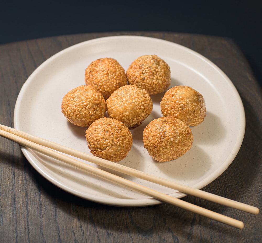 a white plate topped with meatballs and chopsticks