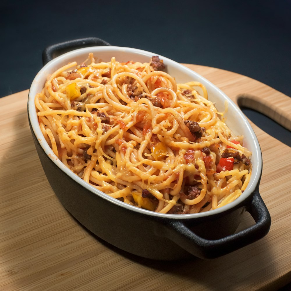 a bowl of spaghetti on a wooden tray
