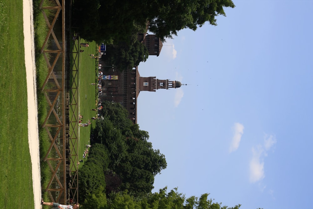 a grassy field with a clock tower in the background