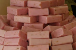 Close-up of pistachio green and light pink handmade soaps stacked neatly.