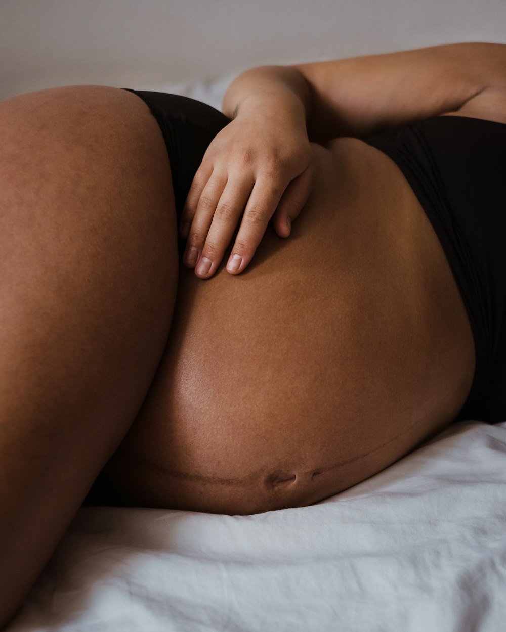 a woman in a black bikini laying on a bed