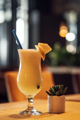 a drink with a blue straw and a pineapple garnish