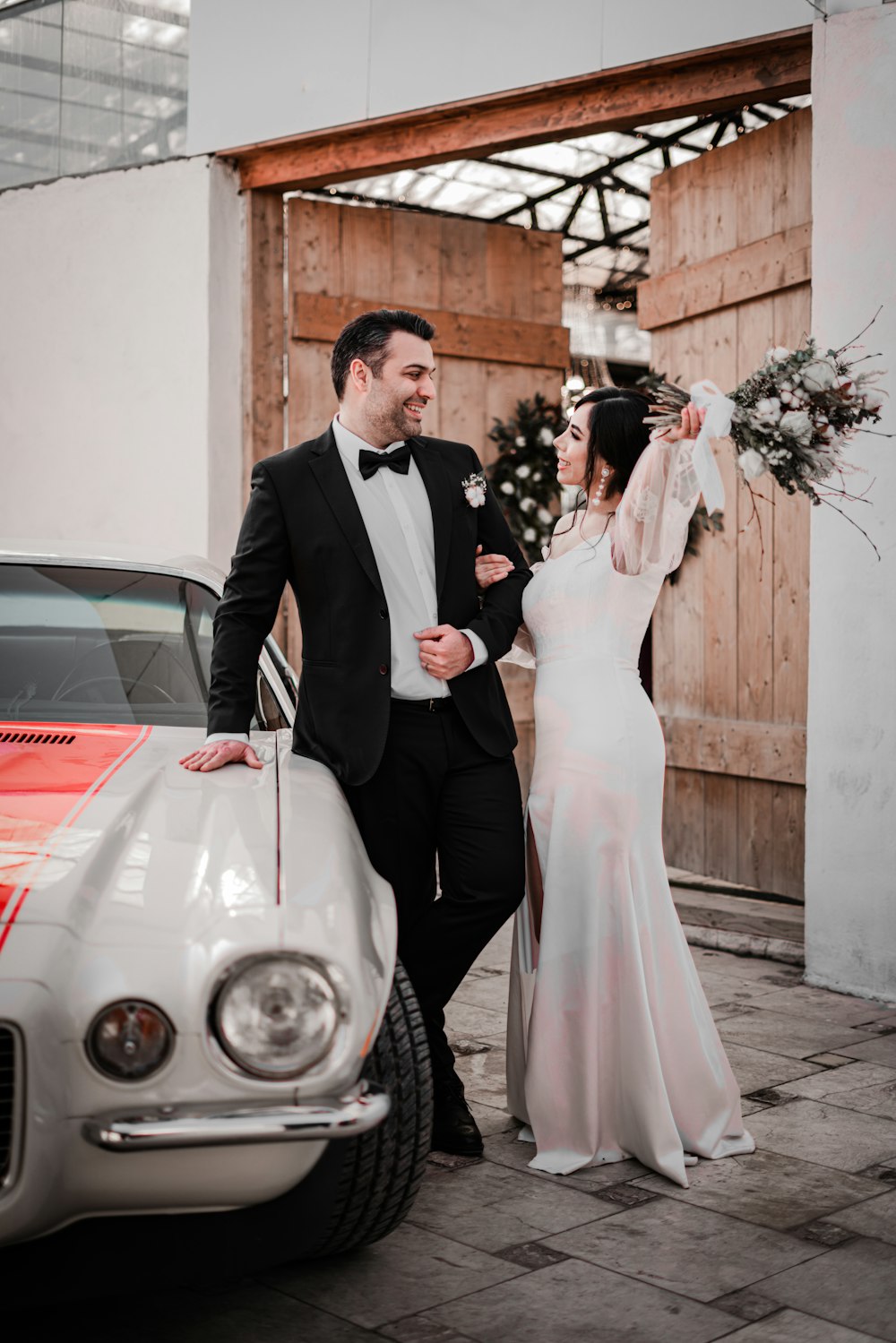 a man and woman standing next to a car