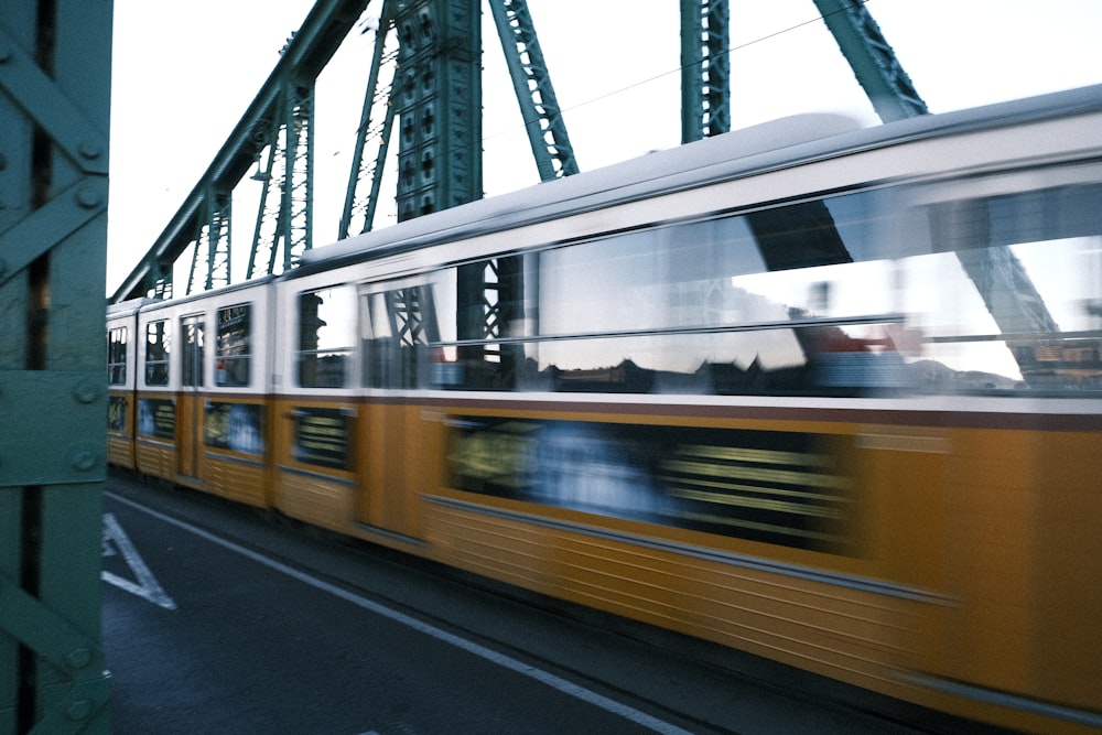 a yellow train traveling across a bridge over water