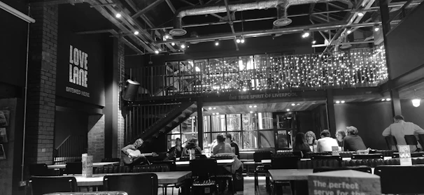 Warmly lit interior of The Black Harp showcasing dark luxury design with patrons enjoying drinks and live music.