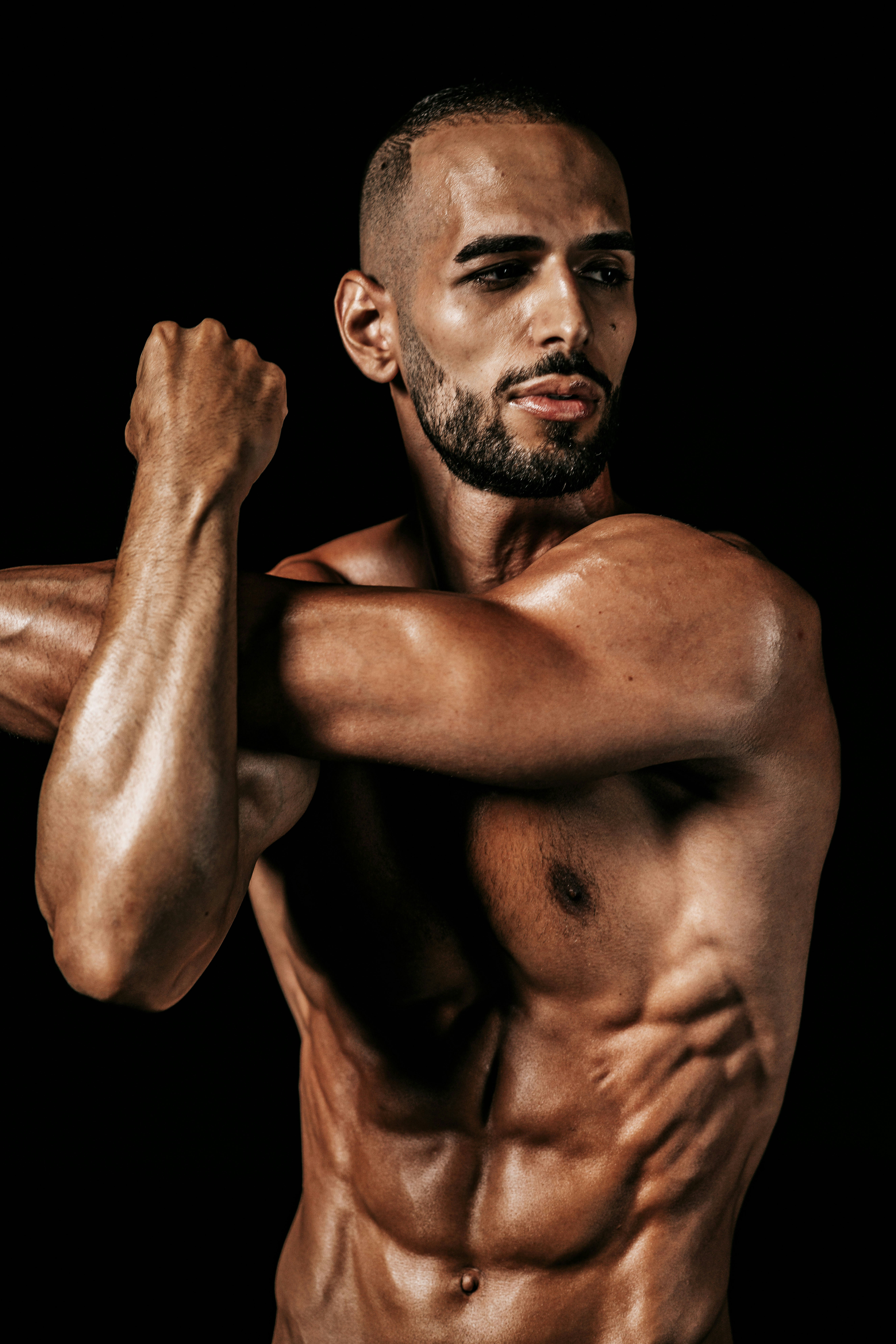 a shirtless man flexing his muscles against a black background