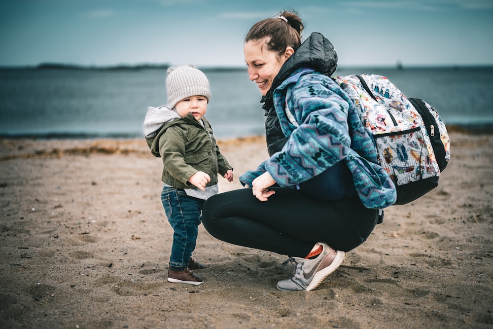 a woman holding a small child's hand on a beach