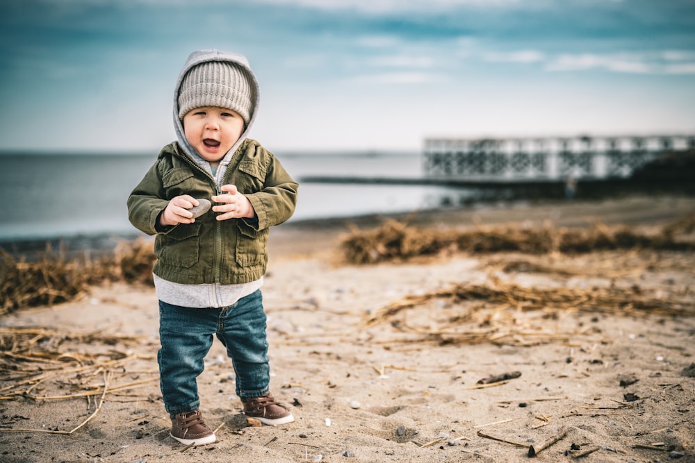 a young boy standing on top of a sandy beach