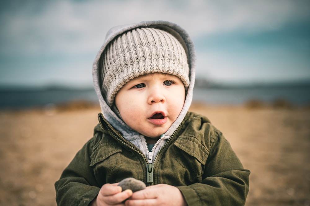 a small child wearing a hat and holding a rock