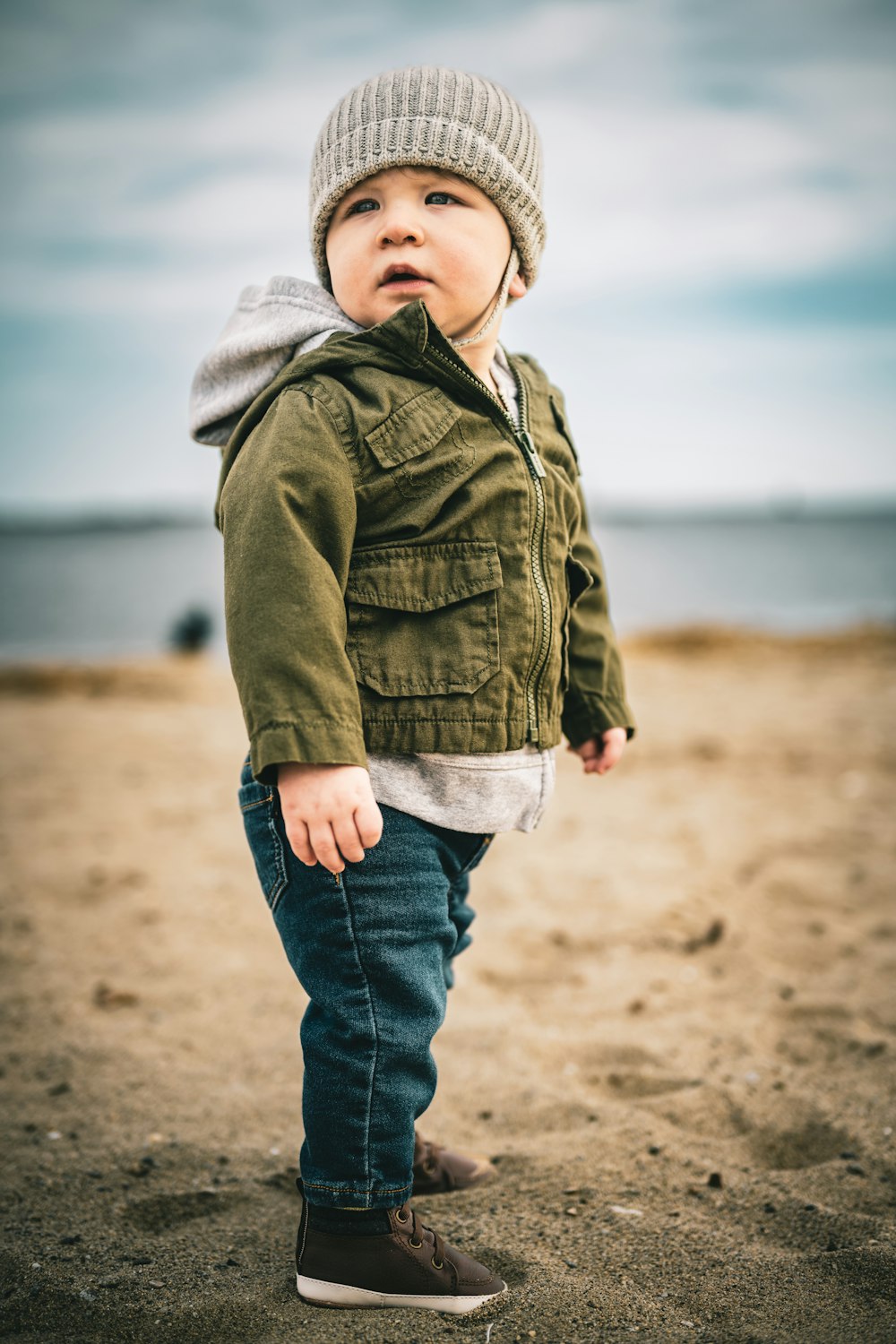 a little boy standing on top of a sandy beach