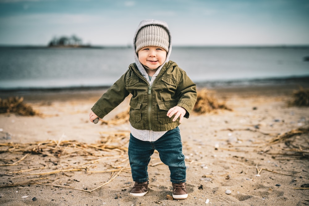 a little boy standing on top of a sandy beach