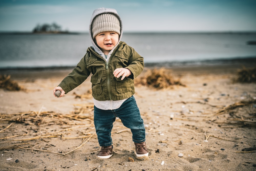 a little boy standing on top of a sandy beach