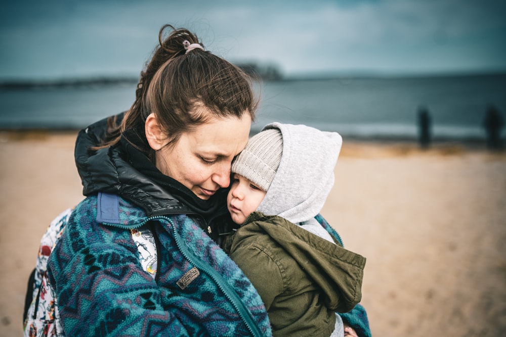 a woman holding a child on the beach