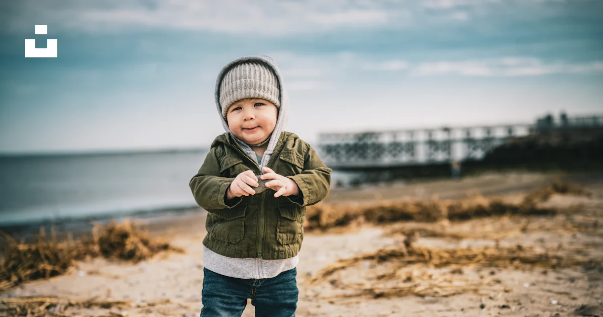 Foto Un niño pequeño parado en la cima de una playa de arena – Imagen ...