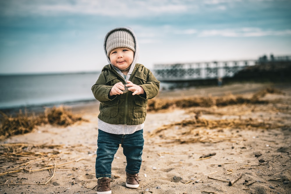 a little boy standing on top of a sandy beach