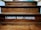 Wooden steps with a motivational quote displayed in bold white letters reading 'I BECOME WHAT I BELIEVE.' The texture of the wood grain is visible, and there is a dim lighting atmosphere.