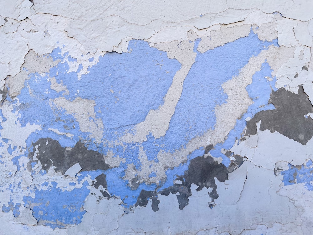 a blue and white wall with peeling paint