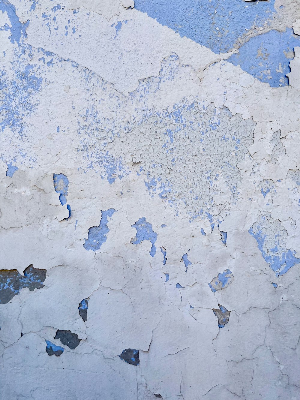 a white and blue wall with peeling paint