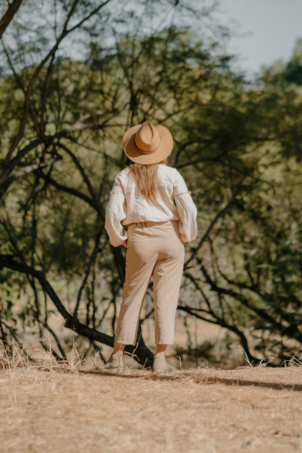 a woman wearing a hat standing in a field