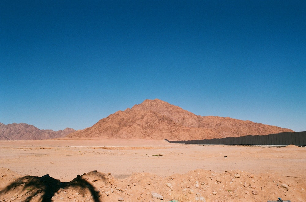 a dirt field with a mountain in the background