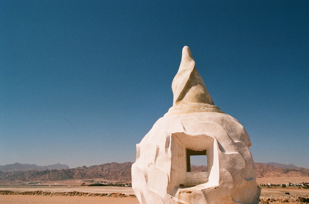 a white sculpture in the middle of a desert