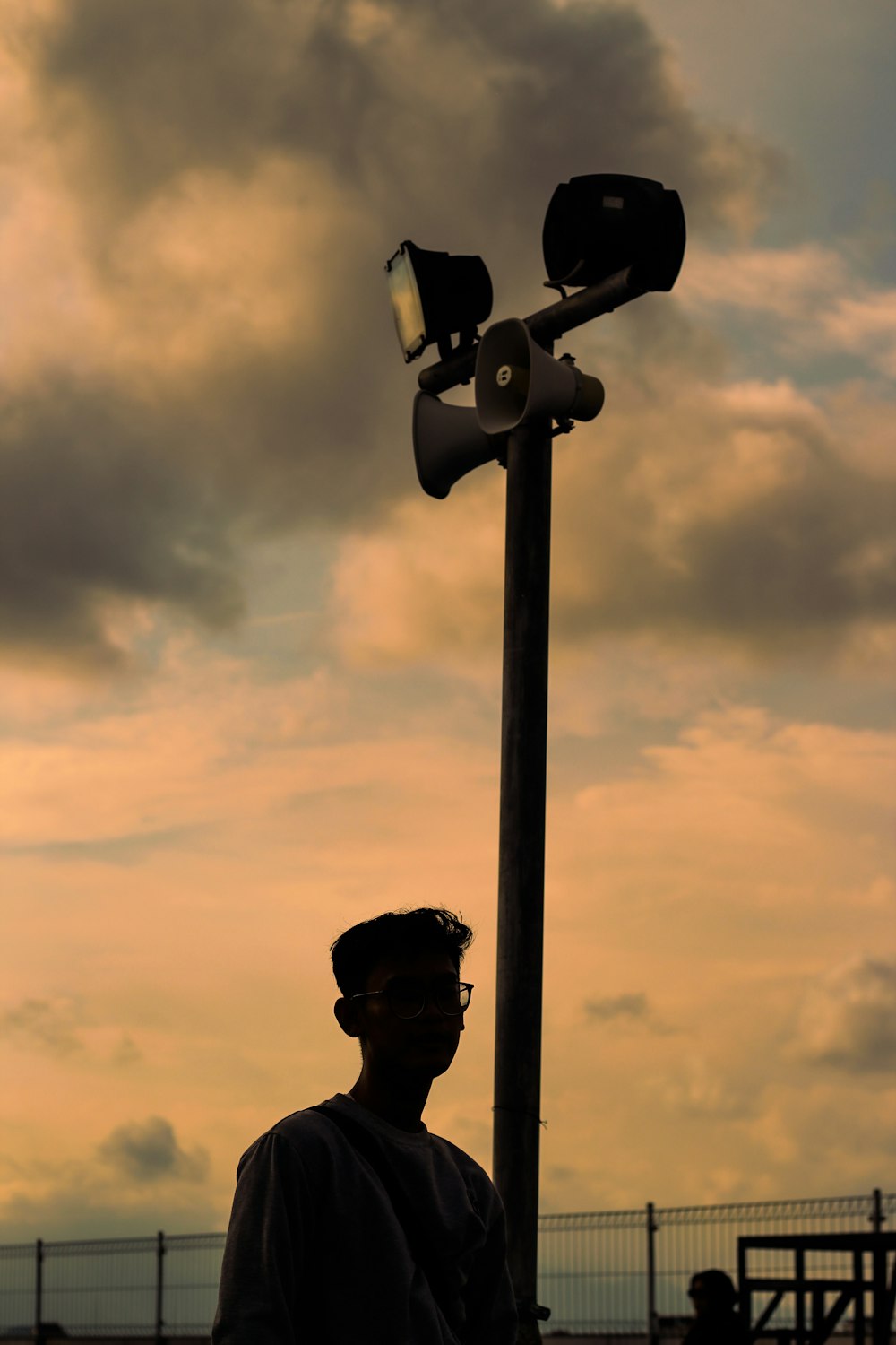 a man standing next to a street light under a cloudy sky