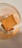 A square butter biscuit is placed inside a clear glass. The glass has orange text and a heart illustration on it. The biscuit is labeled 'LEIBNIZ BUTTERKEKS'.