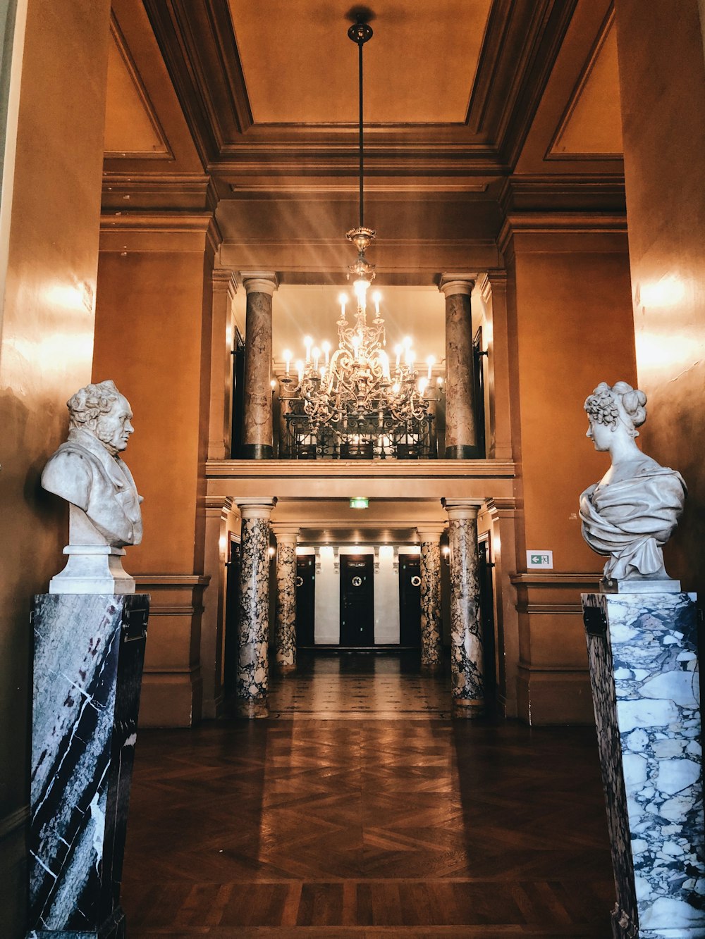 a large hall with a chandelier and marble busturines