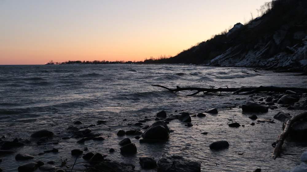 a beach with rocks and water at sunset