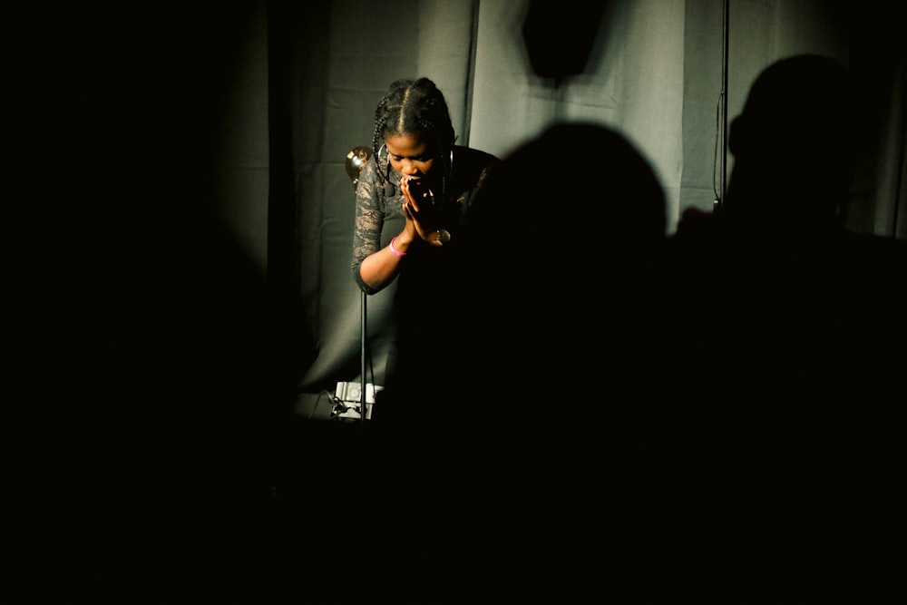 a woman standing in front of a microphone in a dark room