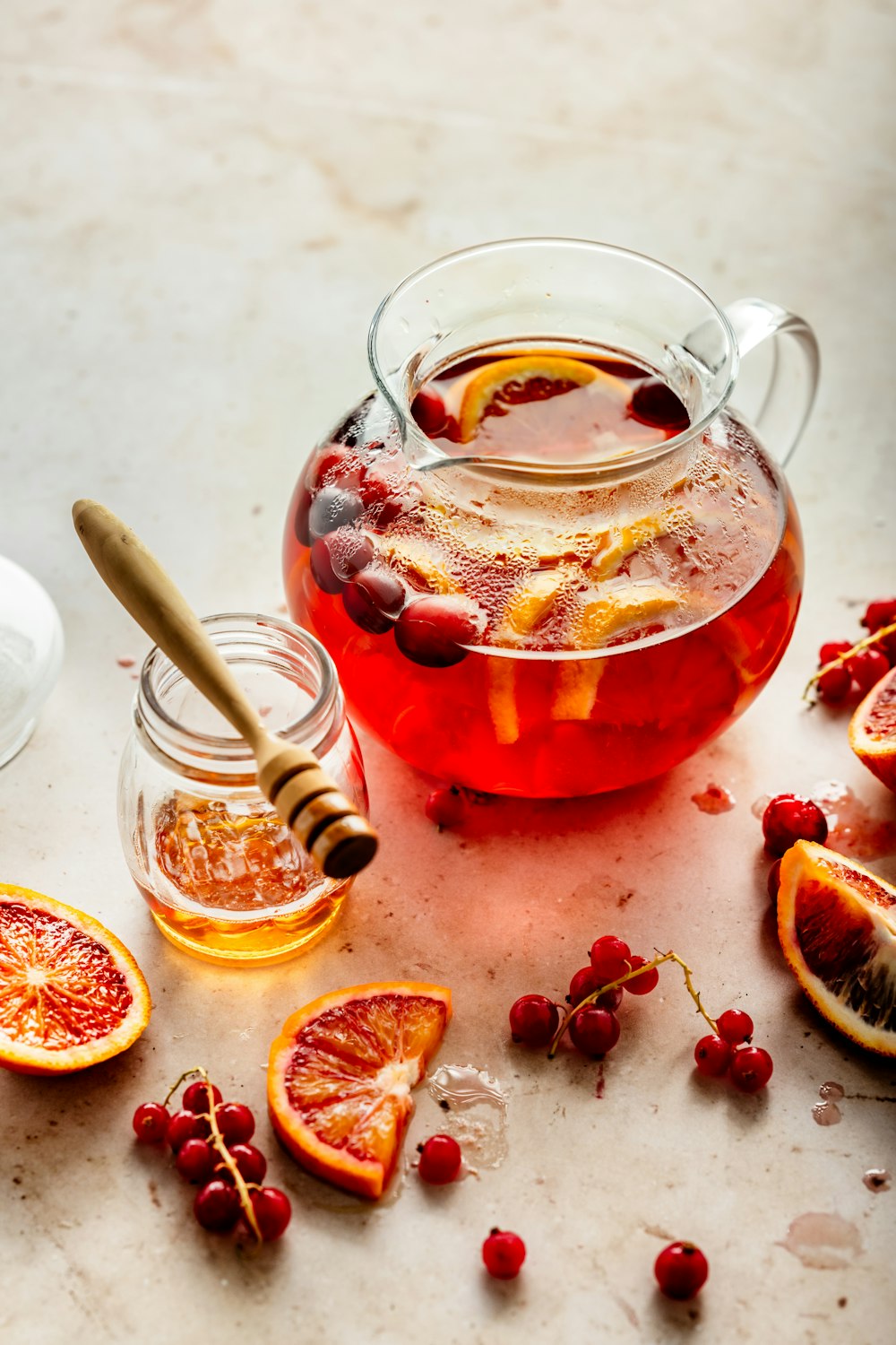 a pitcher filled with liquid next to sliced oranges