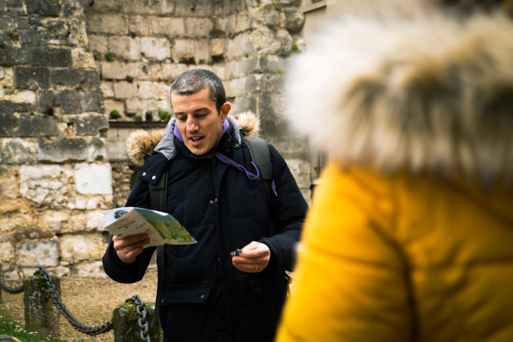 a man standing in front of a stone wall