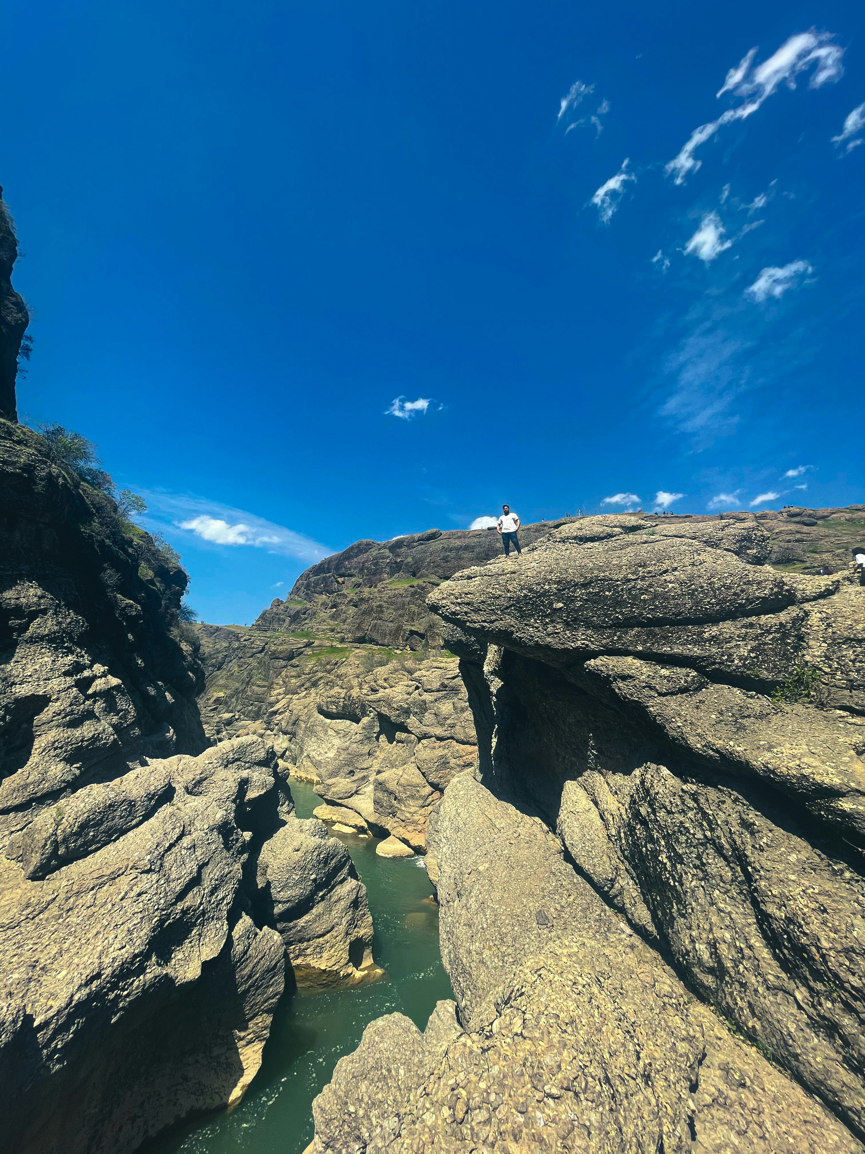 Un hombre parado en la cima de una gran roca junto a un río
