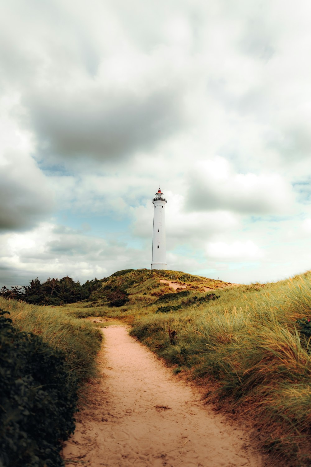 a path leading to a lighthouse on a cloudy day