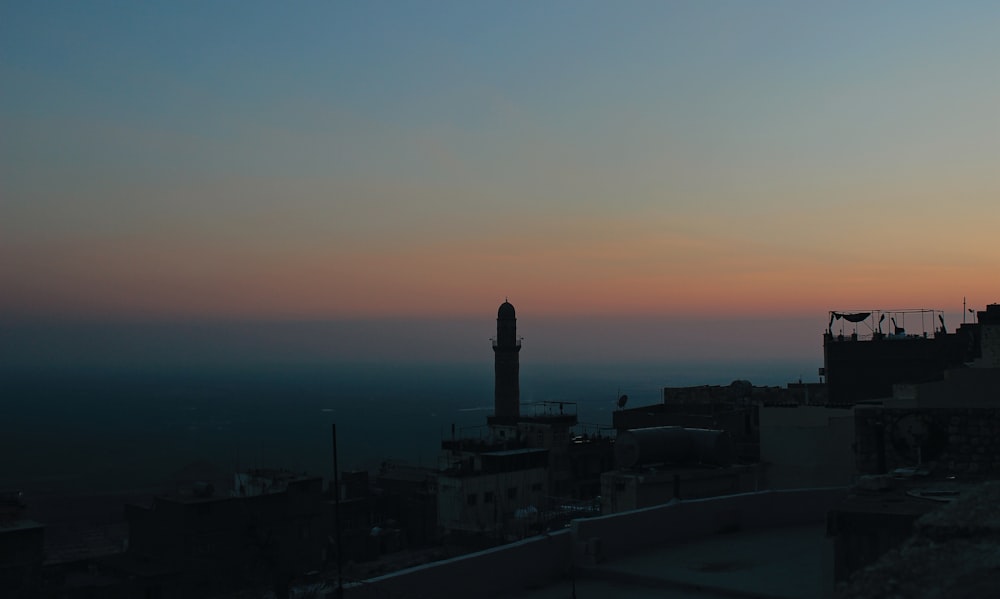 a sunset view of a city with a clock tower in the distance